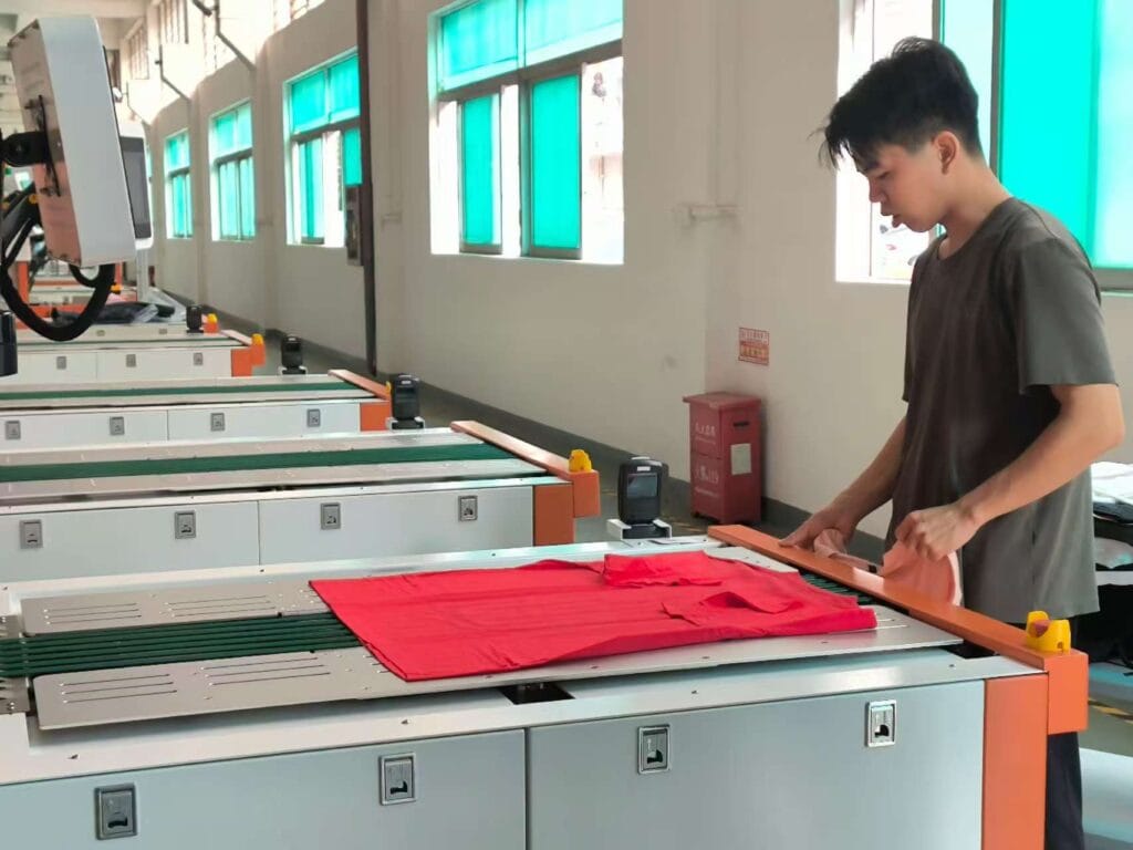 An apparel factory worker efficiently operating a UBL automated garment folding machine, ensuring precise, consistent, and professional T-shirt presentation."